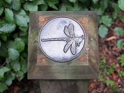 steel embossed dragonfly on a wooden post