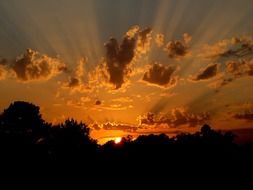 orange rays of the setting sun in the clouds