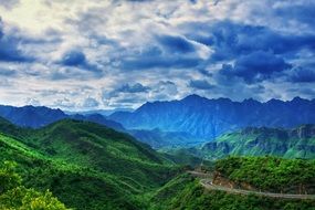 Mountains with green plants under a cloudy sky