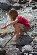 Little girl barefoot on the rocks by the stream