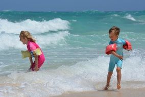 children play in the waves of the surf