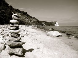 black and white photo of a pyramid of stones on the seashore