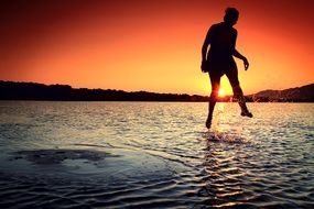 girl jumping on the water at sunset
