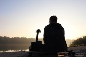 musician with a guitar by the lake