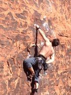 athlete with bare chest climbs on a rock