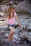 Little girl with long hair on the rocks near the pond