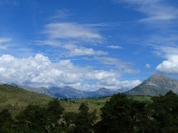 sky with white clouds over picturesque green mountains