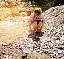 Little blonde girl watching stones on the ground