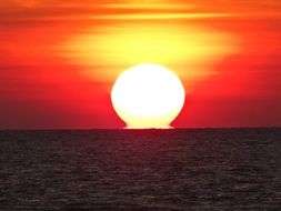 Huge bright sun over the water at sunset