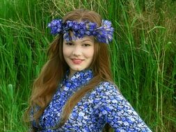 beautiful girl with a wreath on a background of green grass