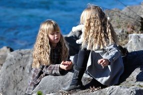 Two girls with white hair on the rocks on the shore