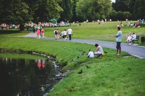 people in park feeding pigeons