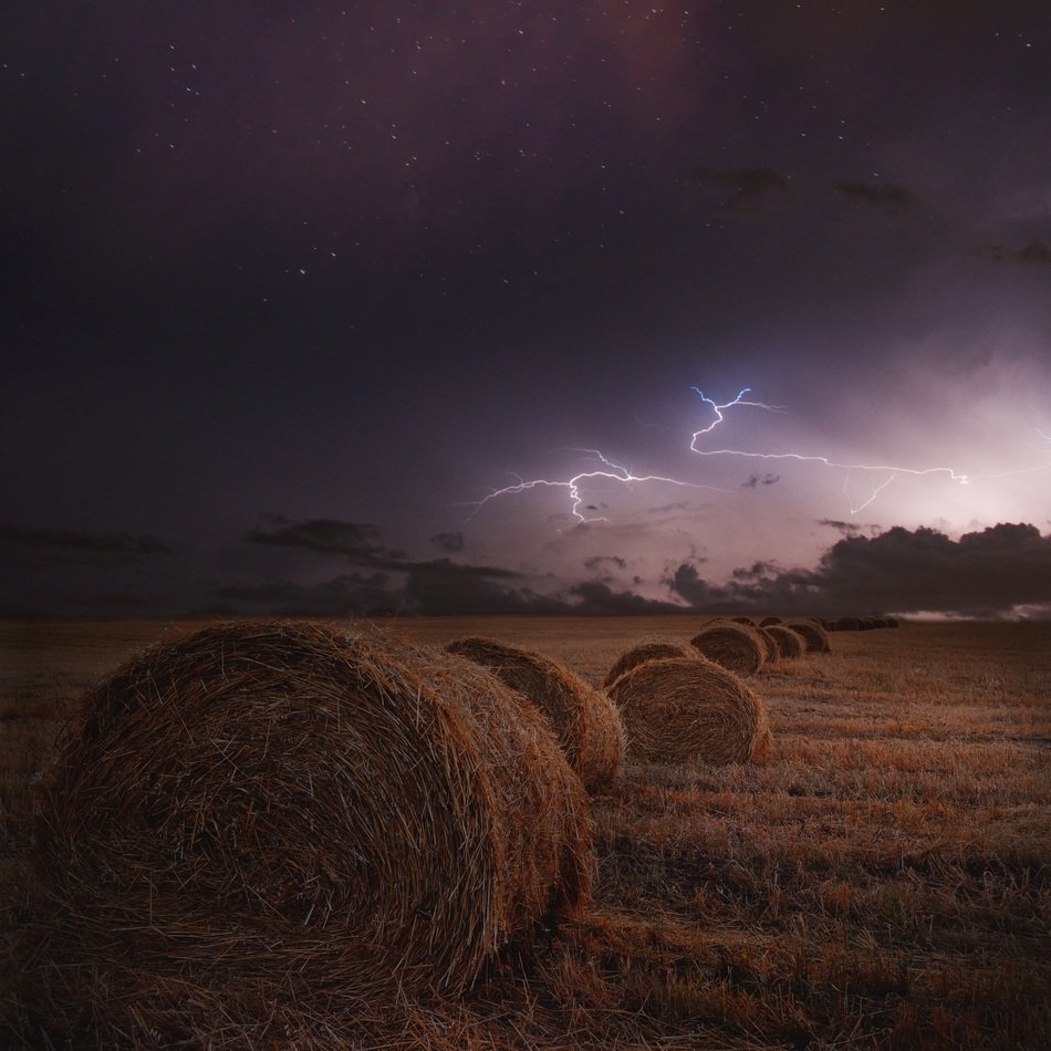 haystacks under a purple stormy sky