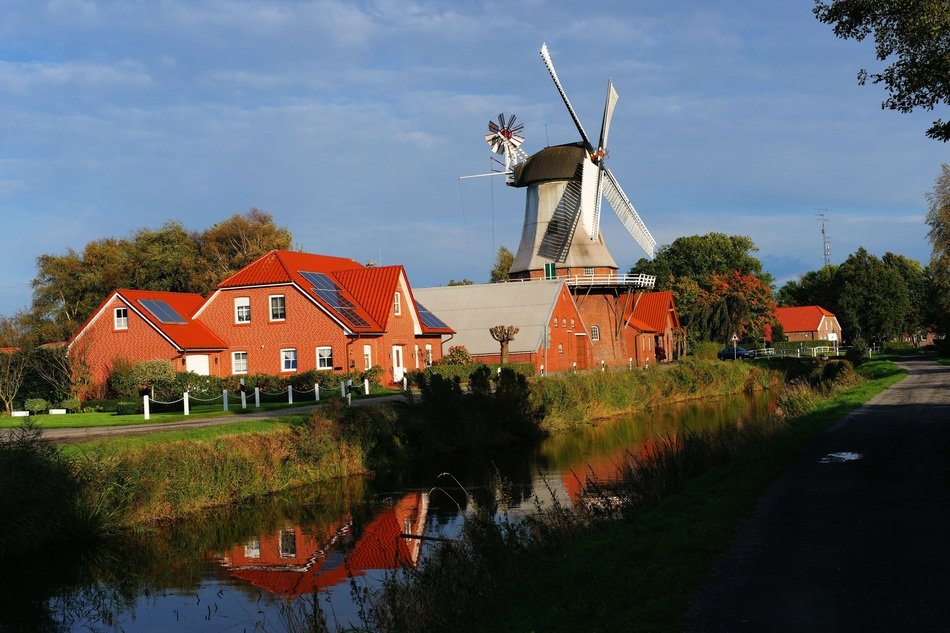 windmill surrounded bricks houses reflected in water