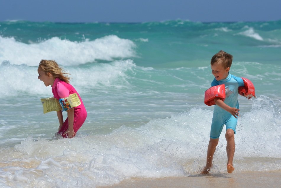 children play in the waves of the surf