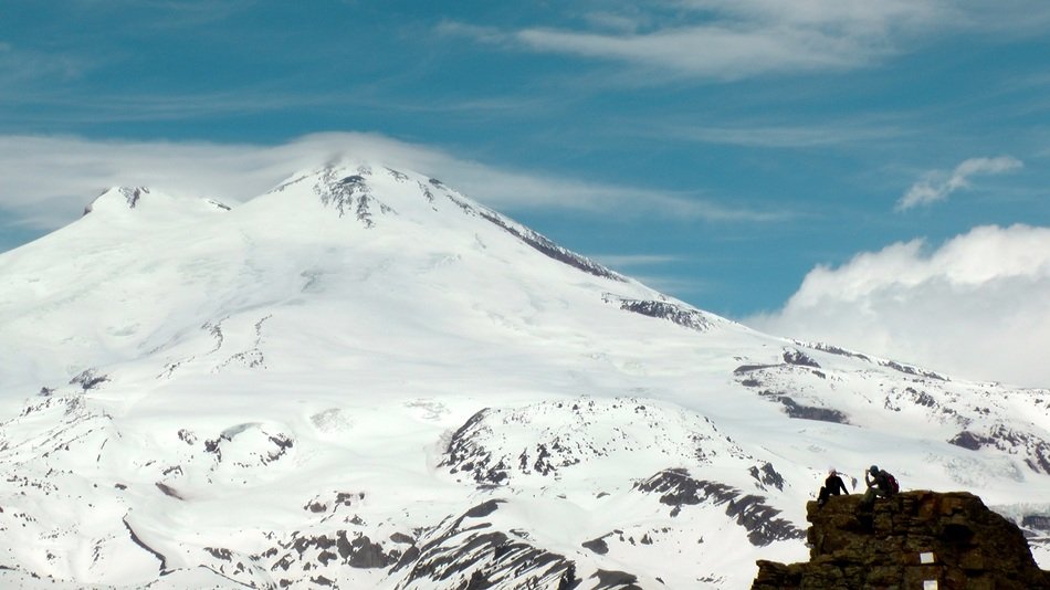 the top of the mountain in the snow on the background of the cloudy sky