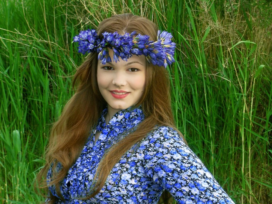 beautiful girl with a wreath on a background of green grass