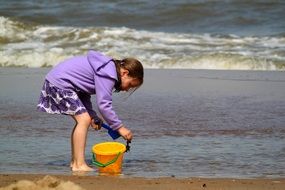 little girl plays on a sandy beach