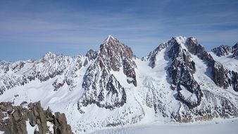 Beautiful, delightful and snowy mountains under blue sky with white clouds in winter