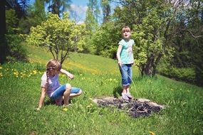 Little girls near the fire in the open air among the colorful plants