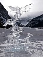 ice carving, human figure with bird and dog on lake louise, canada, alberta