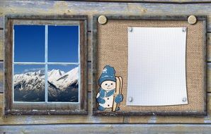 mountain landscape in window and snowman sticker beside blank sheet of paper on board