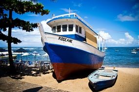 A boat next to a ship on the beach