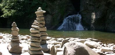 tower of stones on a lake with a waterfall