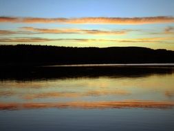 clouds stripes over the lake at colorful sunset on the beautiful landscape