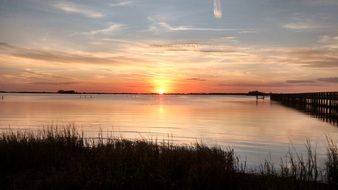 distant view of the orange setting sun in the water