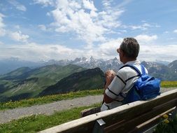 man on a bench looking at mountains