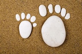 Stone installation of white footprints in the sand with small stones