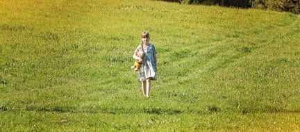 little girl walking in a green meadow