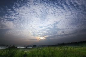white clouds during dawn over a green field