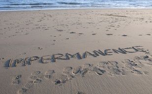 inscription on the sand on the beach "impermanence"