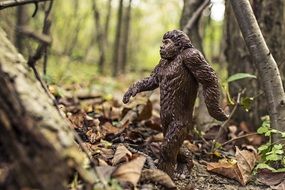 funny brown anthropoid ape toy figurine on forest leaves