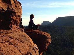 a man in a pose of yoga on a rock