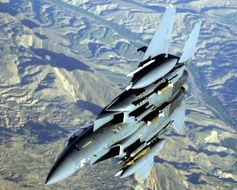 military aircraft in flight over the mountains