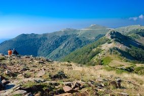 two persons sitting on mountain peak at scenic landscape