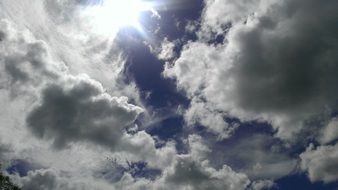 sun shines through clouds in blue sky