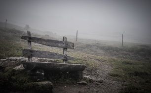 weathered wooden banch on hill side on foggy weather