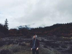 photo of man in front of mountains forest trees