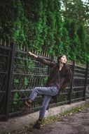 beautiful girl near the black fence near the trees