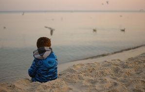 small boy sitting on a beach