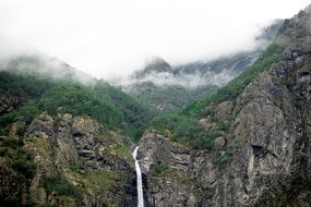 high waterfall in mountains on a cloudy day