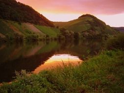 Lake near the green mountains during sunset
