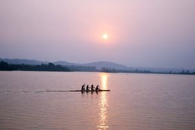 calm sunrise landscape with people on boat silhouettes