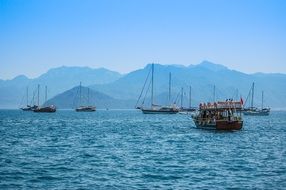 Sailboats on the beautiful blue ocean coast in the background of the mountains