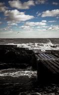 pier on stones in grey sea under blue sky