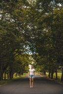 young girl stands on path beneath trees